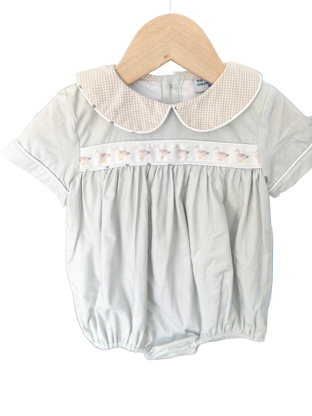 Baby romper with a gingham brown collar and mallard duck ribbon across the bodice.